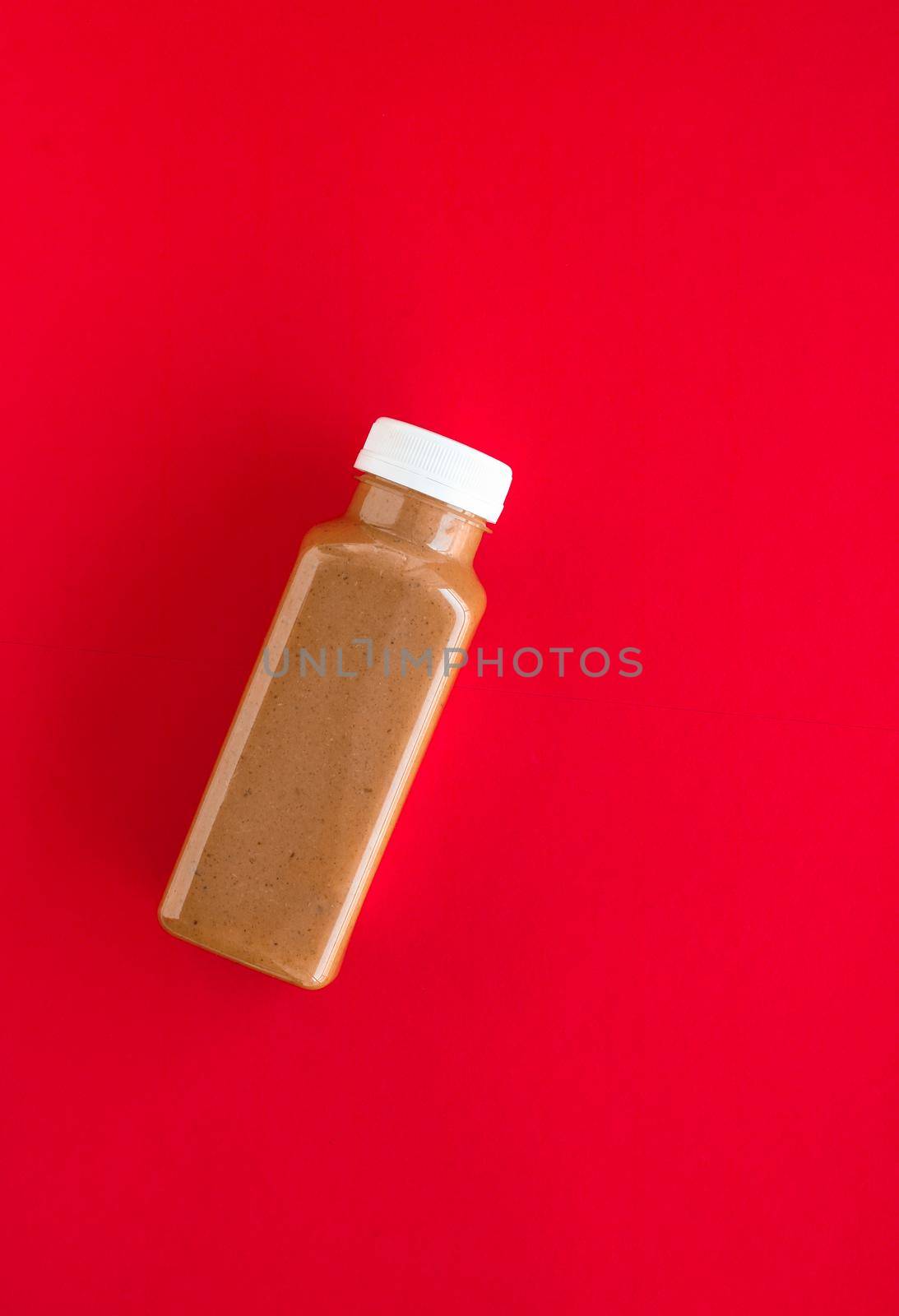 Detox, diet and healthy lifestyle concept - Chocolate banana smoothie bottle on red, flatlay