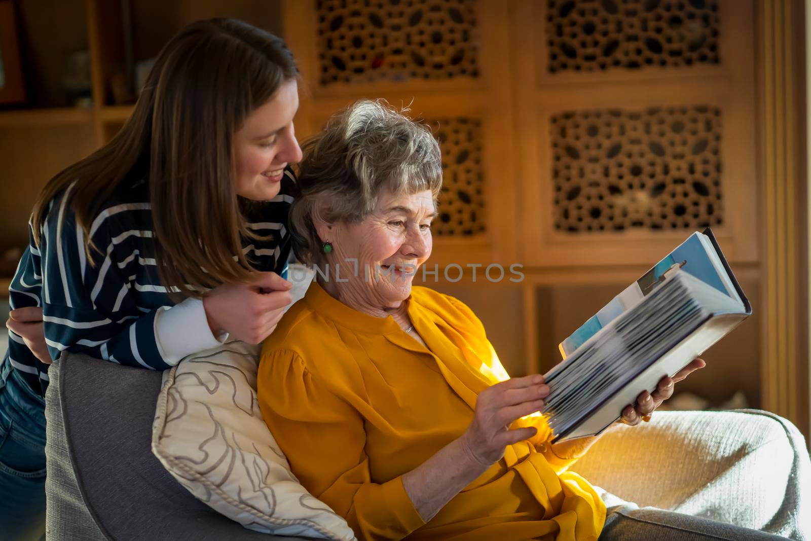 Old woman with her granddaughter look at family photos. by africapink