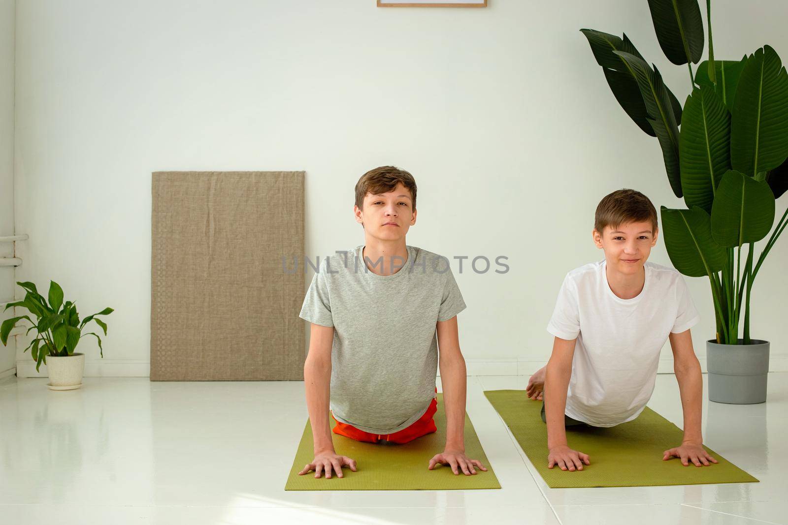 two cute teenagers perform a yoga exercise, on mats by Zakharova