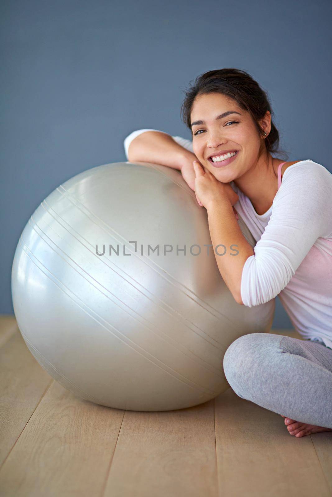 Balling my way to fitness. a sporty young woman leaning against a pilates ball. by YuriArcurs