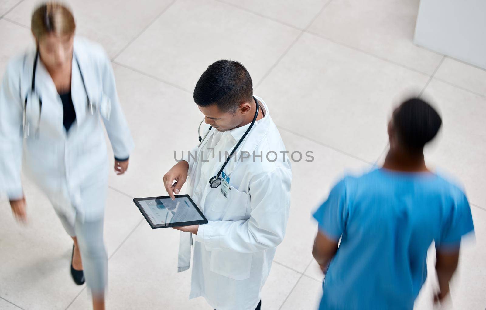 Tablet, healthcare and medicine with a man doctor working in a busy hospital with urgency. Medical, research and insurance with professional workers in medicine rushing with blur in a clinic.