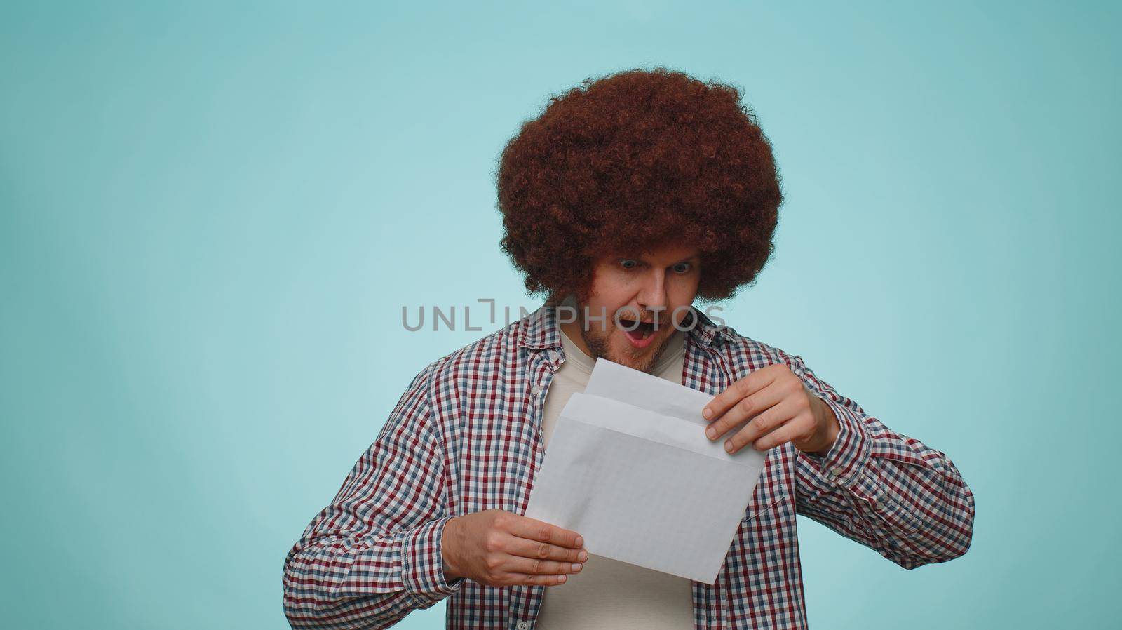 Man open envelope take out letter reads it feel happy. Career growth advance promotion, bank loan approve, monetary award, long-awaited invitation great news. Guy isolated on blue studio background