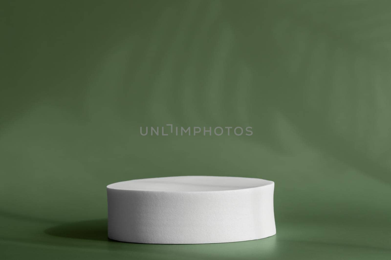 Round pedestal podium for packaging presentation on backdrop with palm leaves shadows from window. Circle platform stage for cosmetic products with shadow on wall. by photolime