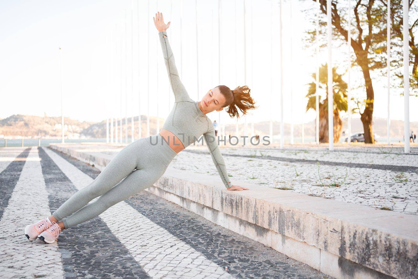 Full length, strong fit girl sportswear training side plank outdoor summer day, doing perfect plank exercise and looking motivated, concentrated on pilates workout. Health care, sport activity