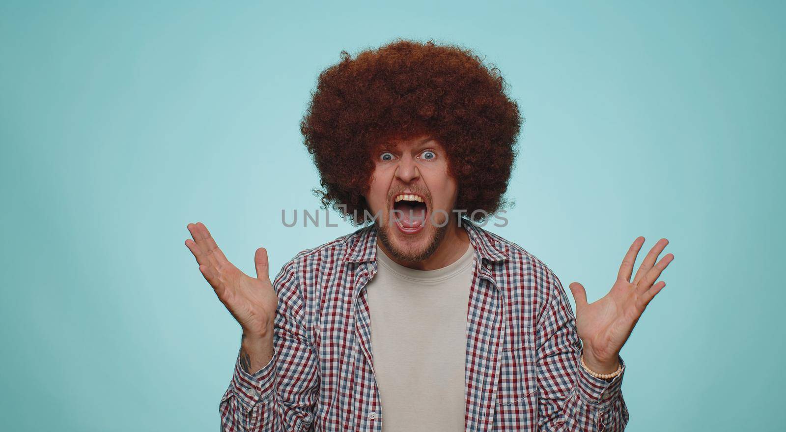 Bearded adult man scared fearful, covering ears with hands, closing eyes, meeting his own phobia, evidence horror event, screaming, shouting at loud, freaked out. Young guy alone on blue background