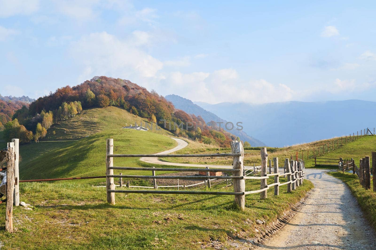 Picturesque Alps autumn landscape, wooden fence and mountain hills in Lombardy, Italy. by photolime