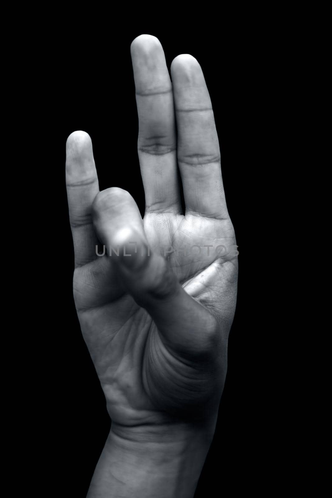 Prithvi mudra demonstrated by male hand isolated on black background.