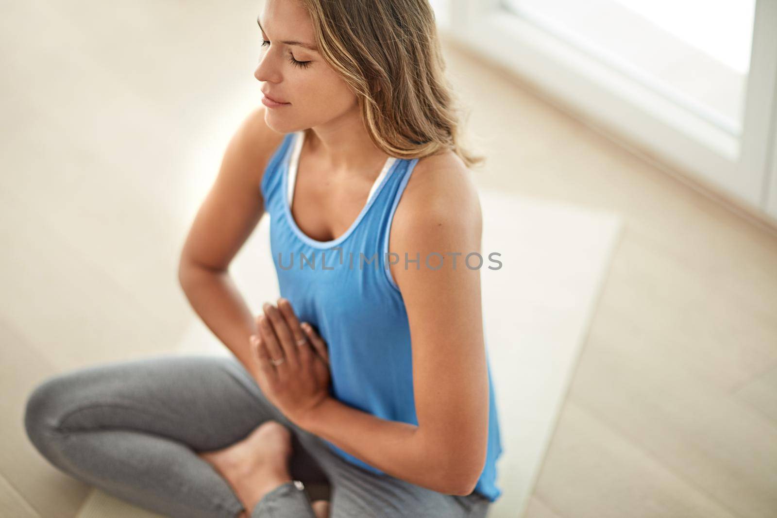 Meditation is part of her lifestyle. a young woman meditating at home. by YuriArcurs