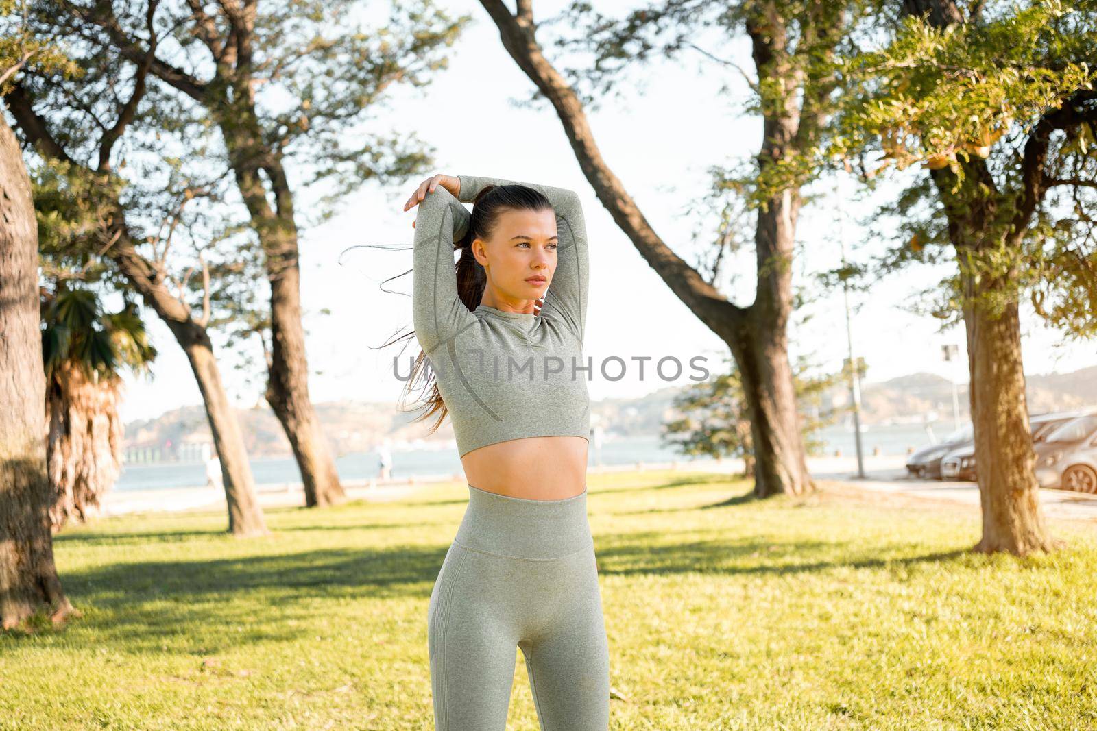 Woman Stretching And Warming-Up Before Running. Fit sport woman stretching her body warm up before workout outdoor. The girl in sportswear exercises outside in summer park for health and wellbeing.