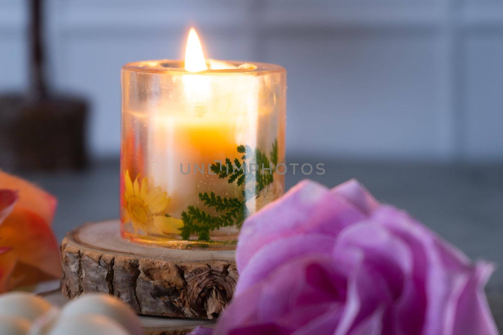 Lit resin art transparent candle on wood coaster with flowers showing the decoration of diwali, christmas, new year shot in pastel shades by Shalinimathur