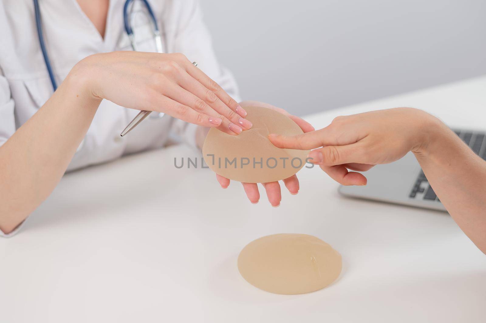 Caucasian woman and plastic surgeon choosing breast implants. by mrwed54