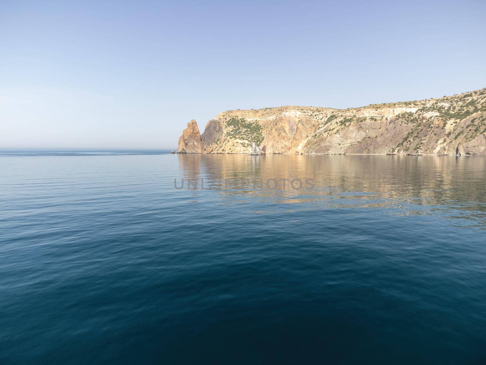 Sea landscape with rocky coastline on sunset time with cloudy sky. Yachts in the Sea on a background of rocky shores. The concept of perfect place for summer travel and rest.