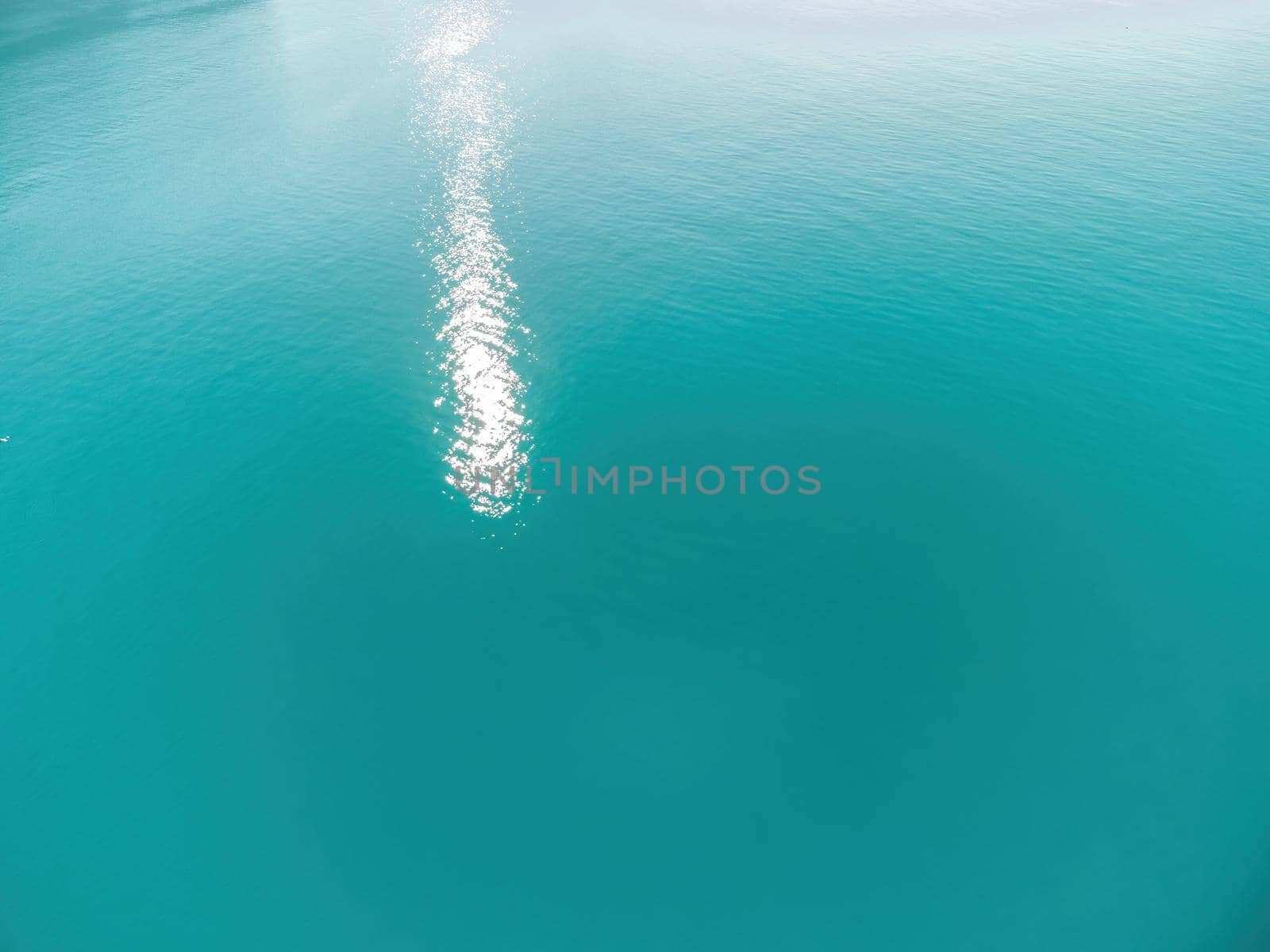 Abstract aerial sea summer ocean sunset nature background. Small waves on azure water surface in motion blur with golden bokeh lights from sun. Holiday, vacation and recreational concept. Slow motion by panophotograph