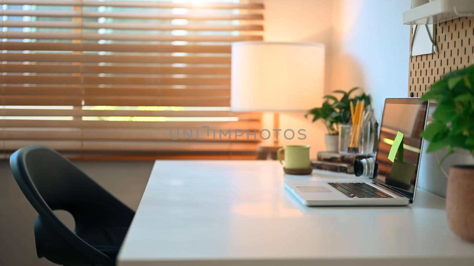 Comfortable home office with laptop , coffee cup, houseplant and supplies on white table.