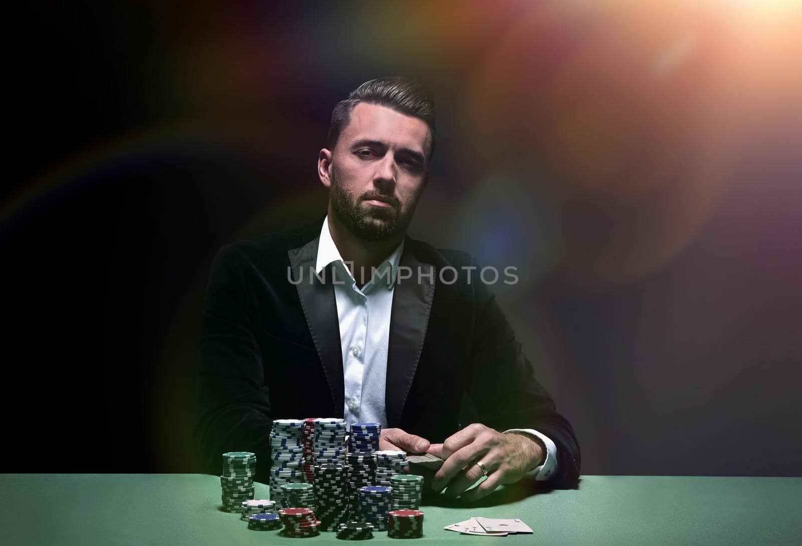 Young man sitting at the poker table with his chips and cards in front of him