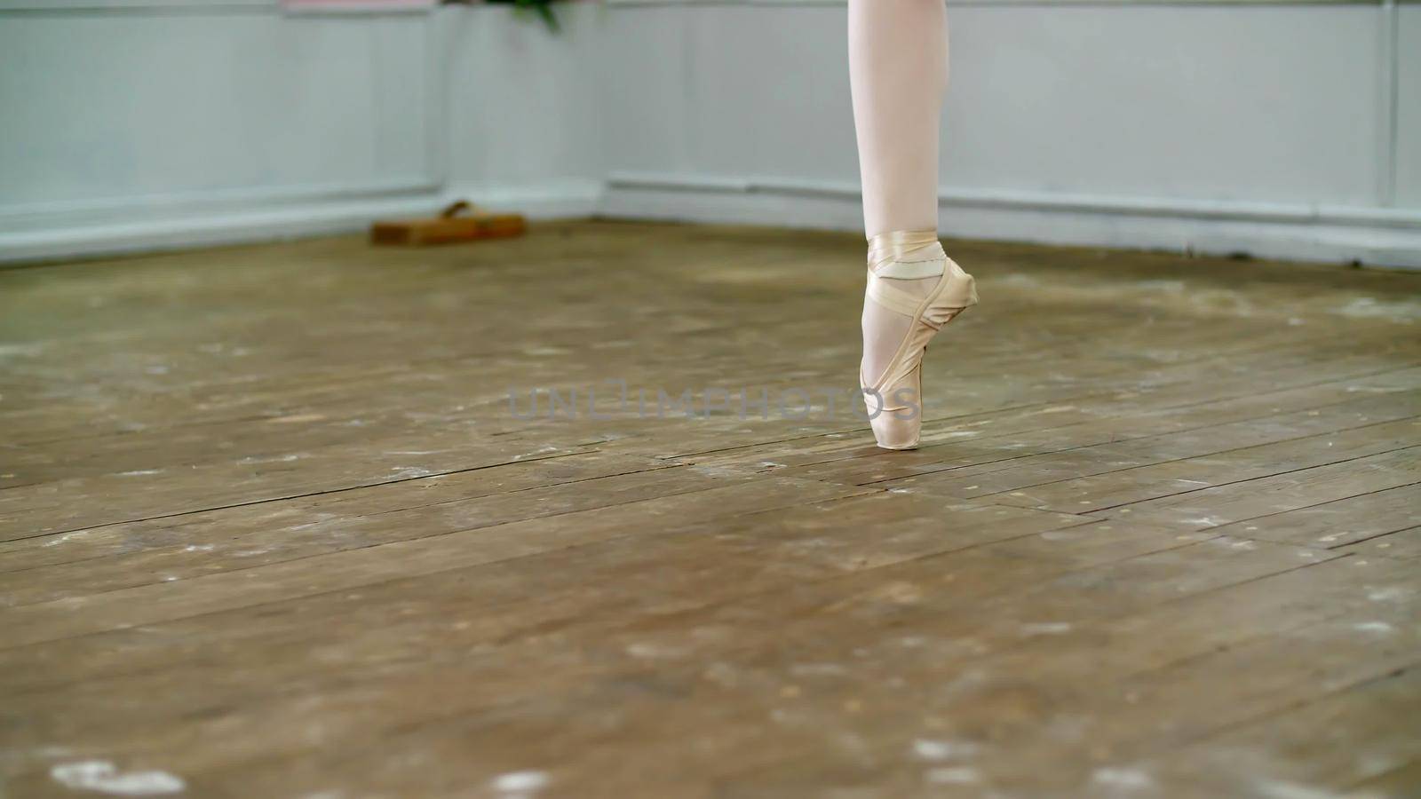 close up, in dancing hall, ballerina perform step pointe , She is standing on toes in pointe shoes elegantly , on an old wooden floor, in ballet class. High quality photo