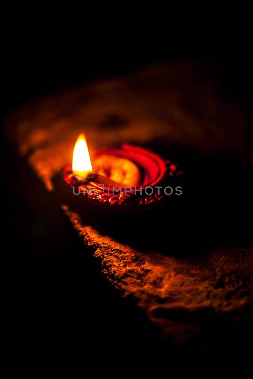 Close-up shot of burning Diva or divida or Diya or oil lamp isolated in dark. by mirzamlk