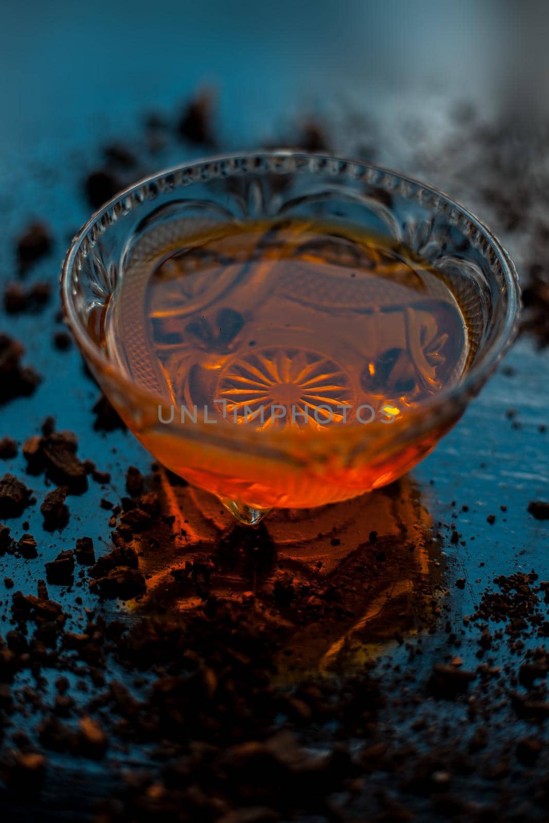 Close-up shot of honey in a glass bowl on the black surface along with some raw cocoa powder sprinkled on it.