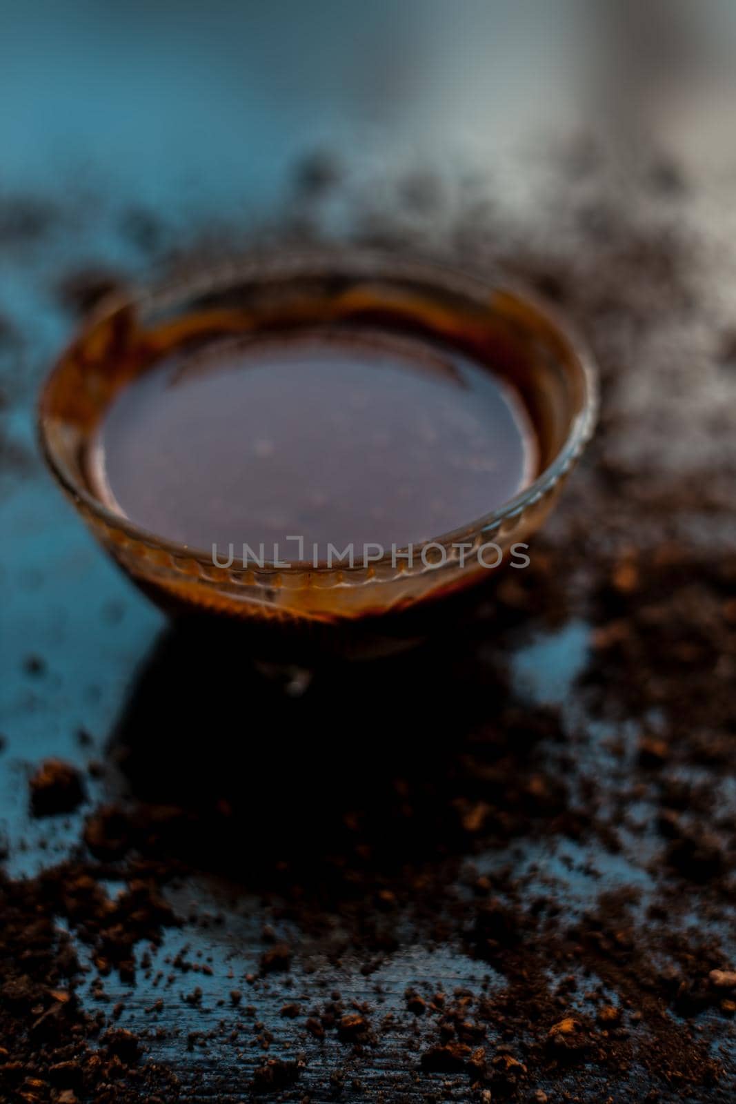 A bowl full of chocolate milk on a black wooden surface with some raw cocoa powder sprinkled around it.