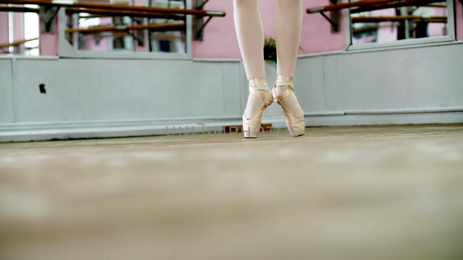 close up, in dancing hall, ballerina perform ssissonne simples , She is standing on toes in pointe shoes elegantly , on an old wooden floor, in ballet class. High quality photo