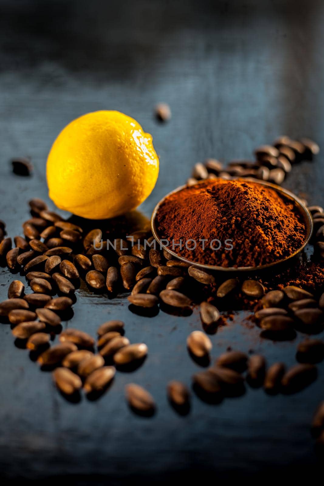 Best home remedy or face mask to remove tan at home consisting of some coffee beans powder and lemon juice on a black colored wooden surface.