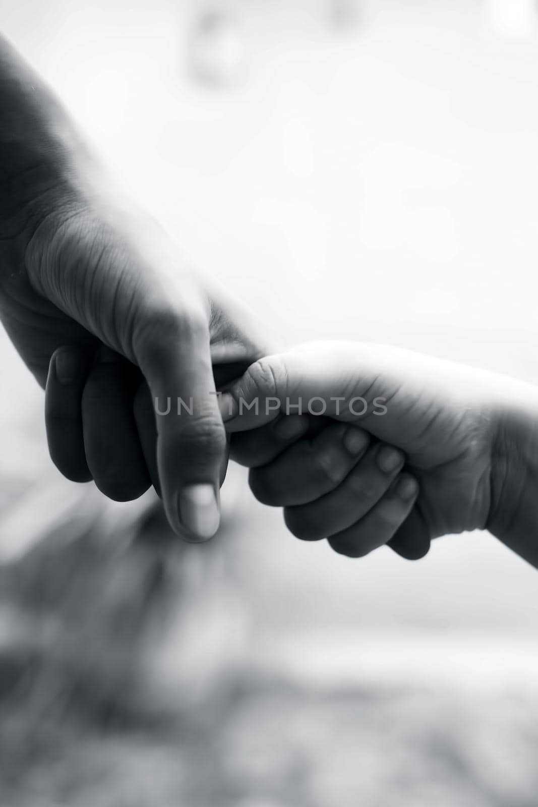 Hand of female child holding the hand of matured man, Shot with blurred background. Concept of Father’s day. Men helping the female hand to overcome conquer obstacles and fears. Vertical shot.