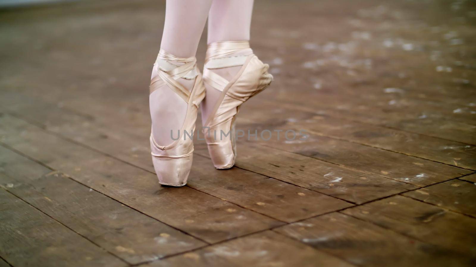 close up, in dancing hall, ballerina perform step pointe , She is standing on toes in pointe shoes elegantly , on an old wooden floor, in ballet class. High quality photo