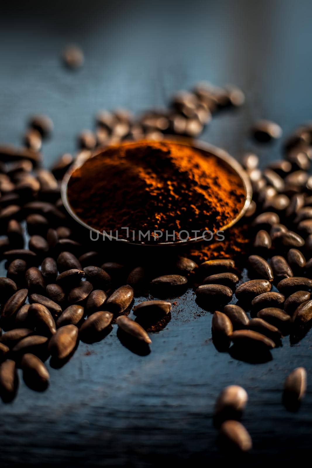 Shot of raw coffee beans and powder on a black surface.