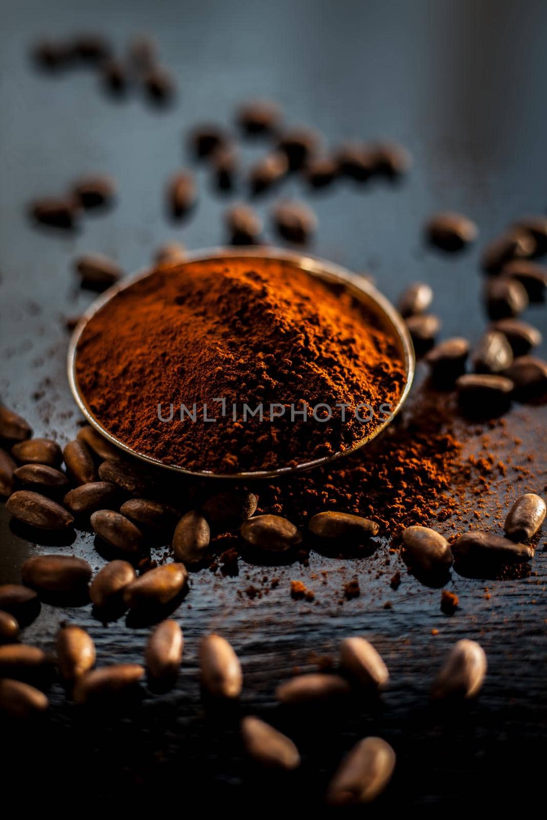 Shot of raw coffee beans and powder on a black surface.