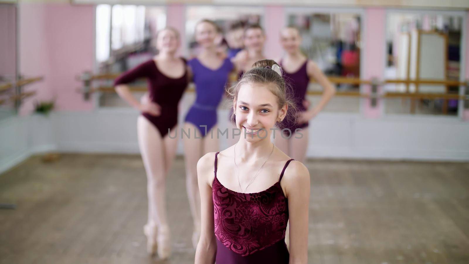 portrait of a young girl ballet dancer in a lilac ballet leotard, smiling, gracefully performing a ballet figure. High quality photo