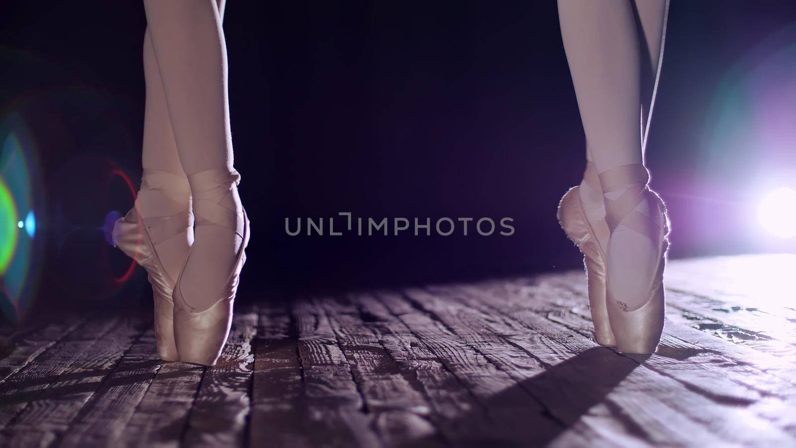 close up, in rays of spotlight, on the stage of the old theater hall. ballerinas standing on toes in pointe shoes, performs elegantly a certain ballet exercise, pas de bourre suivi. High quality photo