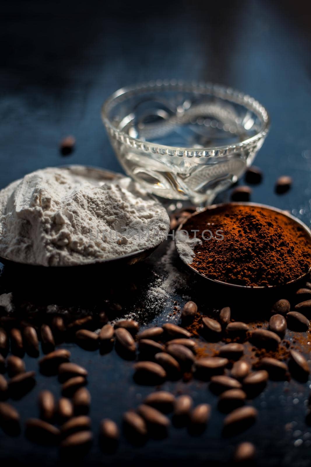 Coffee face mask for skin whitening on a black shiny wooden surface consisting of some coffee powder, lukewarm water, and rice flour. by mirzamlk