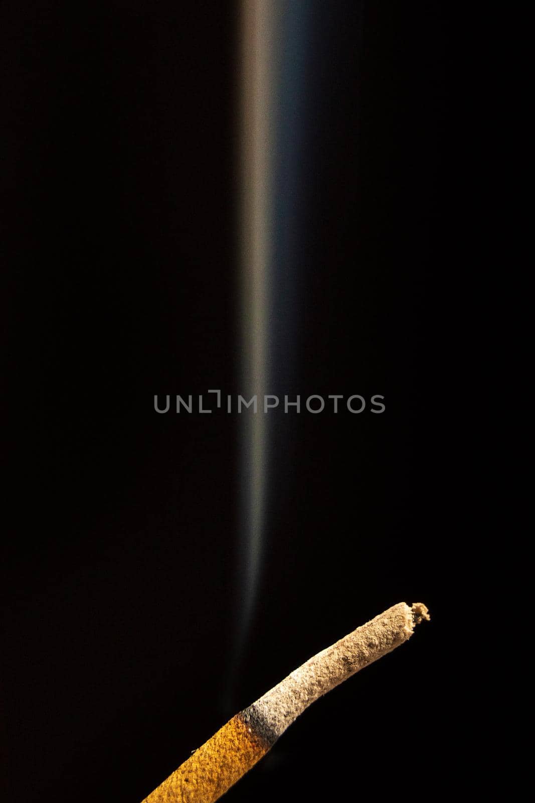 Close-up of smoking stick of incense isolated on a black background.