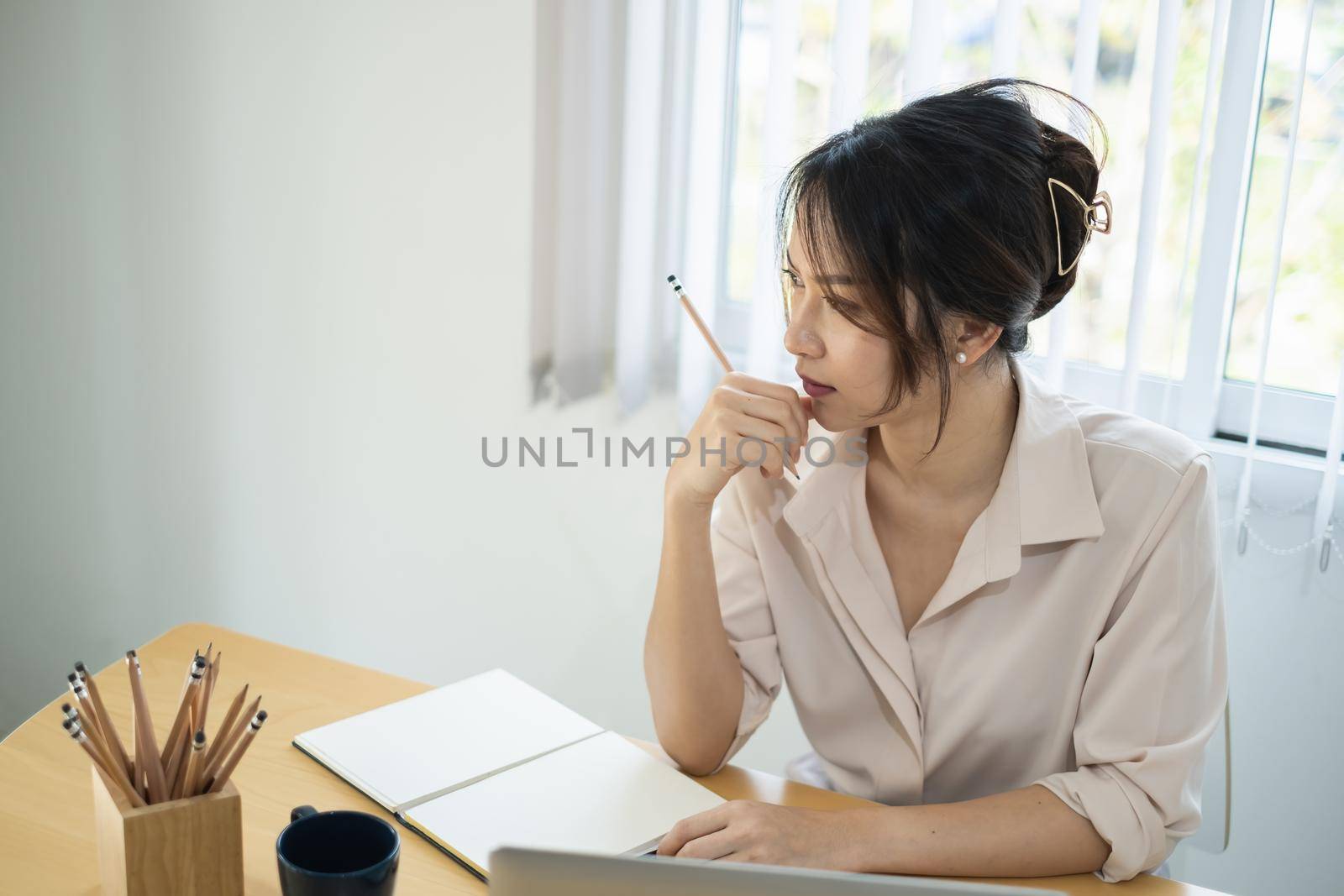 Asian Business woman sitting in office with laptop computer on wooden desk.