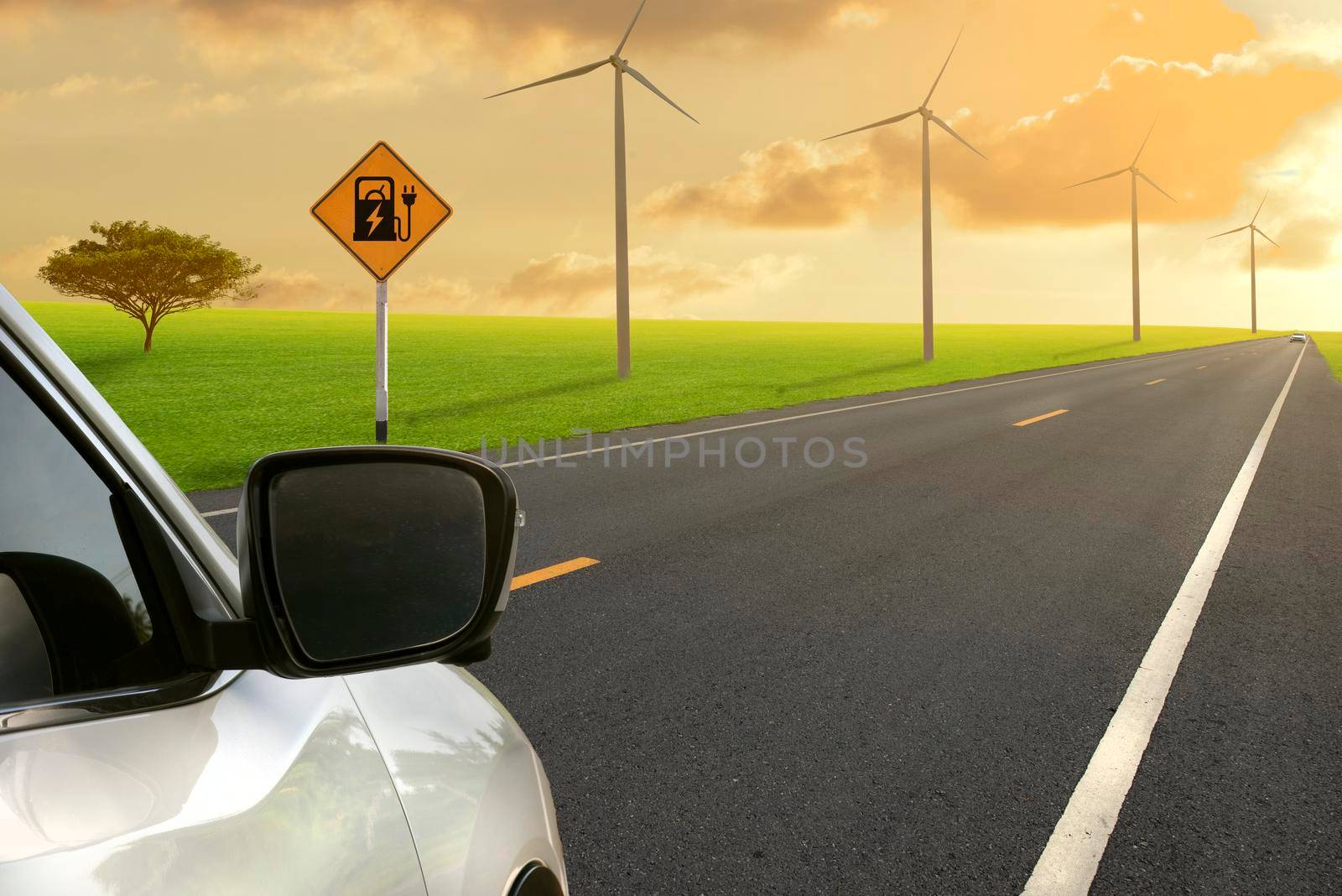 Road in green field and Electric car road sign charging station with wind turbines backgrounds.