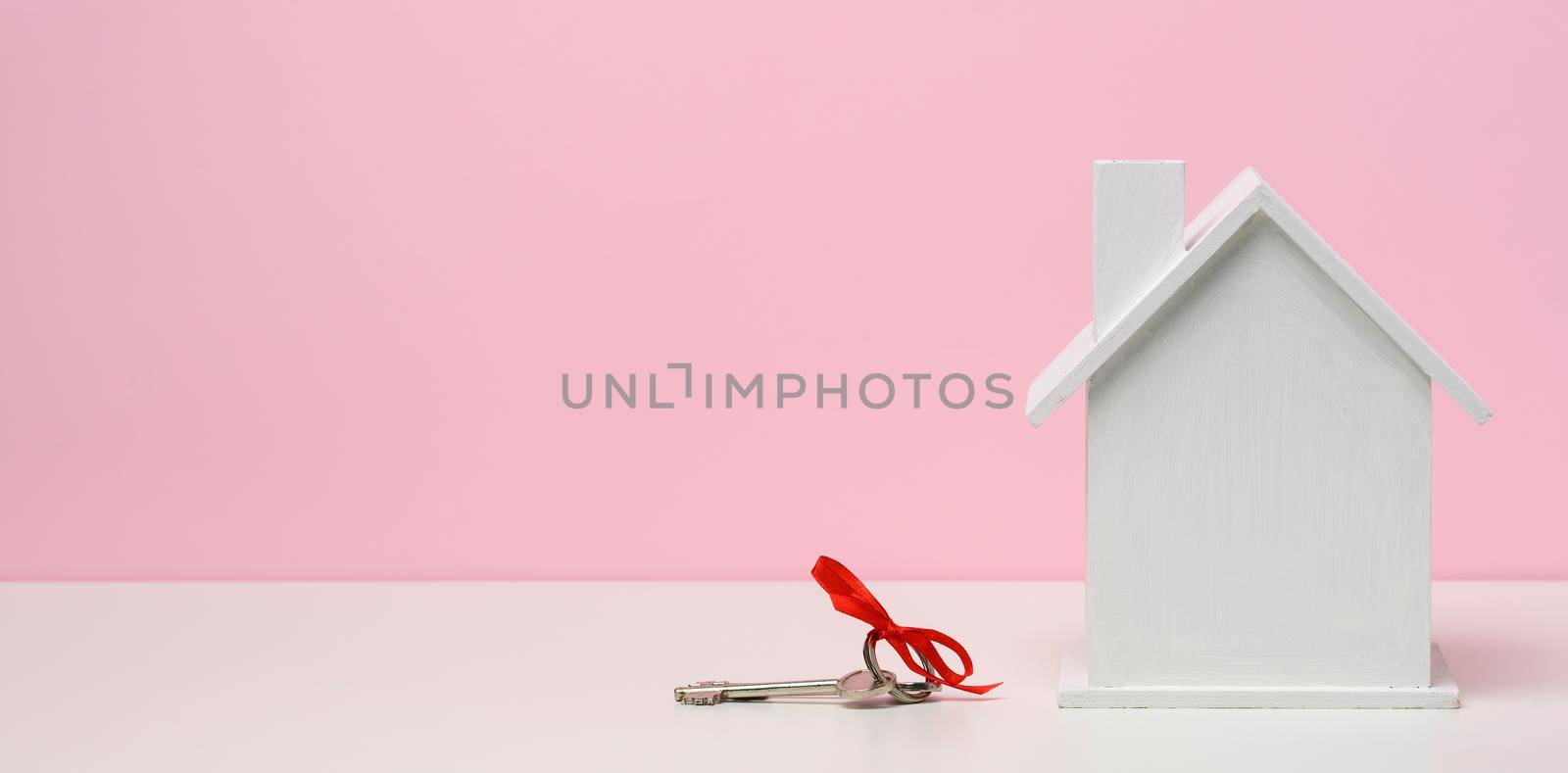 wooden house on a pink background. Real estate rental, purchase and sale concept. Realtor services, building repair and maintenance, copy space