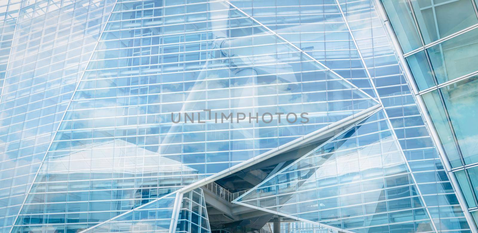 Sustainable glass building and wind power concept. Wind turbine and blue sky reflect on sustainable corporate office building. Green energy. Sustainable development goals concept. Renewable energy.