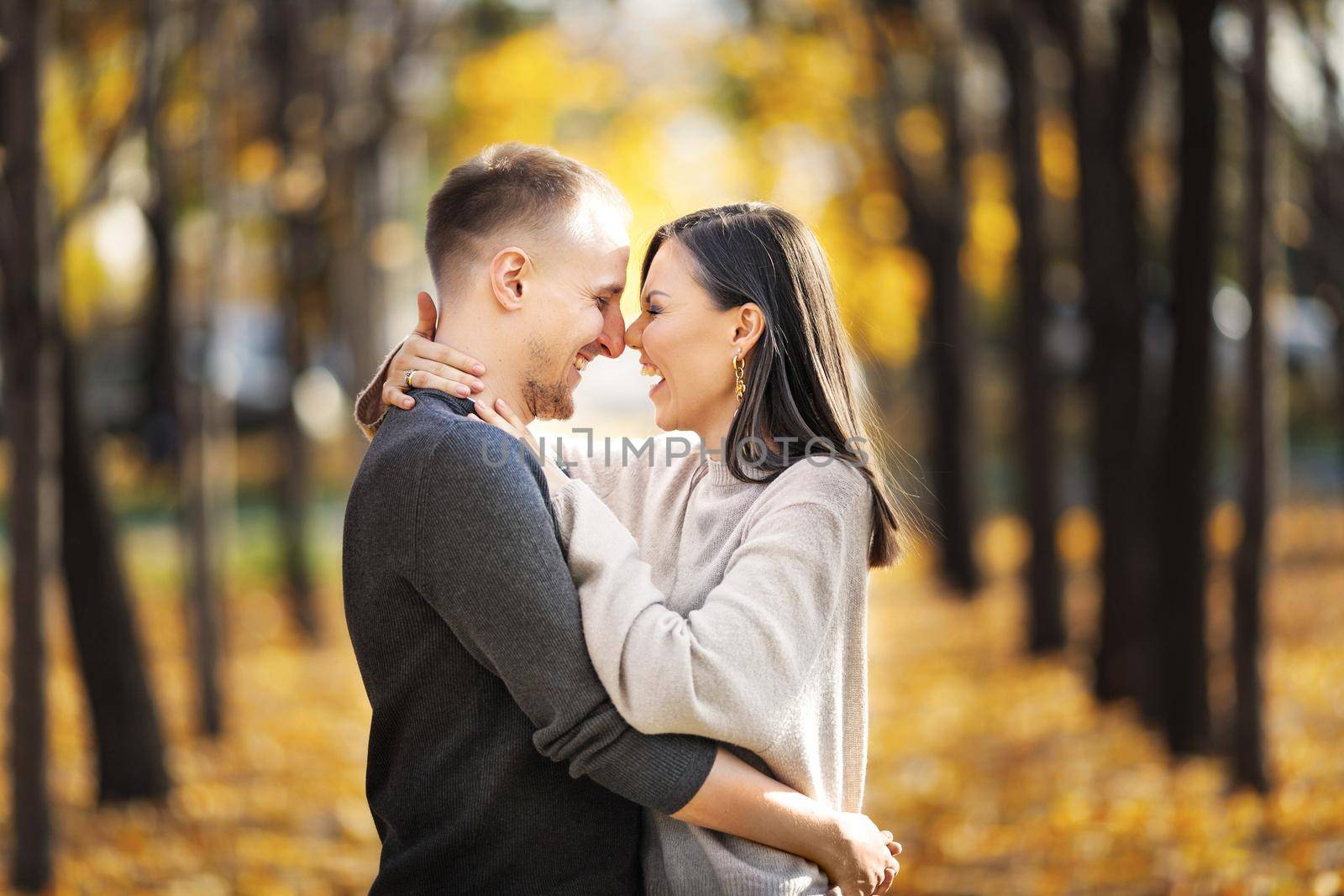 Young happy couple in love on a date laughing and hugging in autumn park by Rom4ek