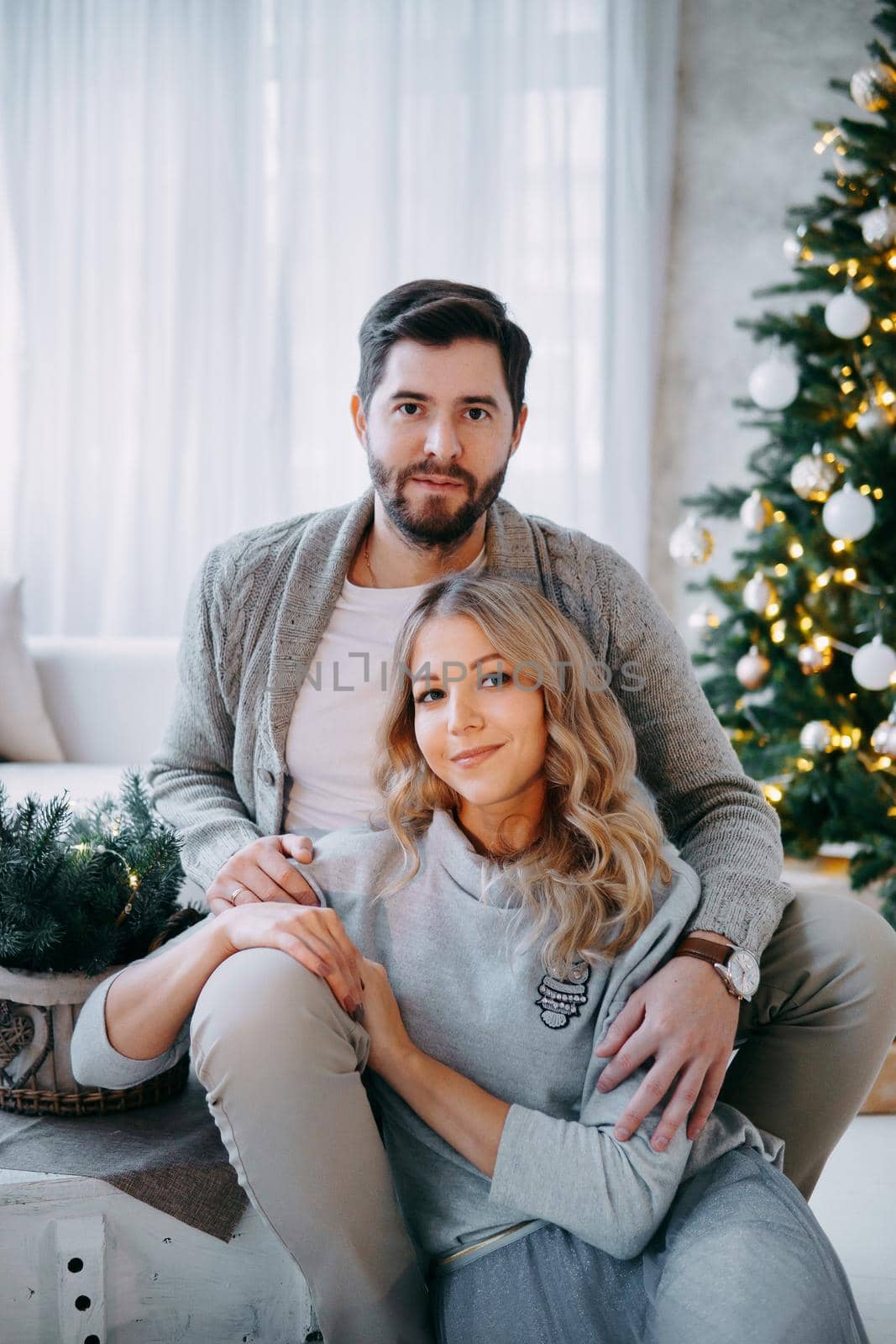 A happy couple in love - a man and a woman. A family in a bright New Year's interior with a Christmas tree. by Annu1tochka