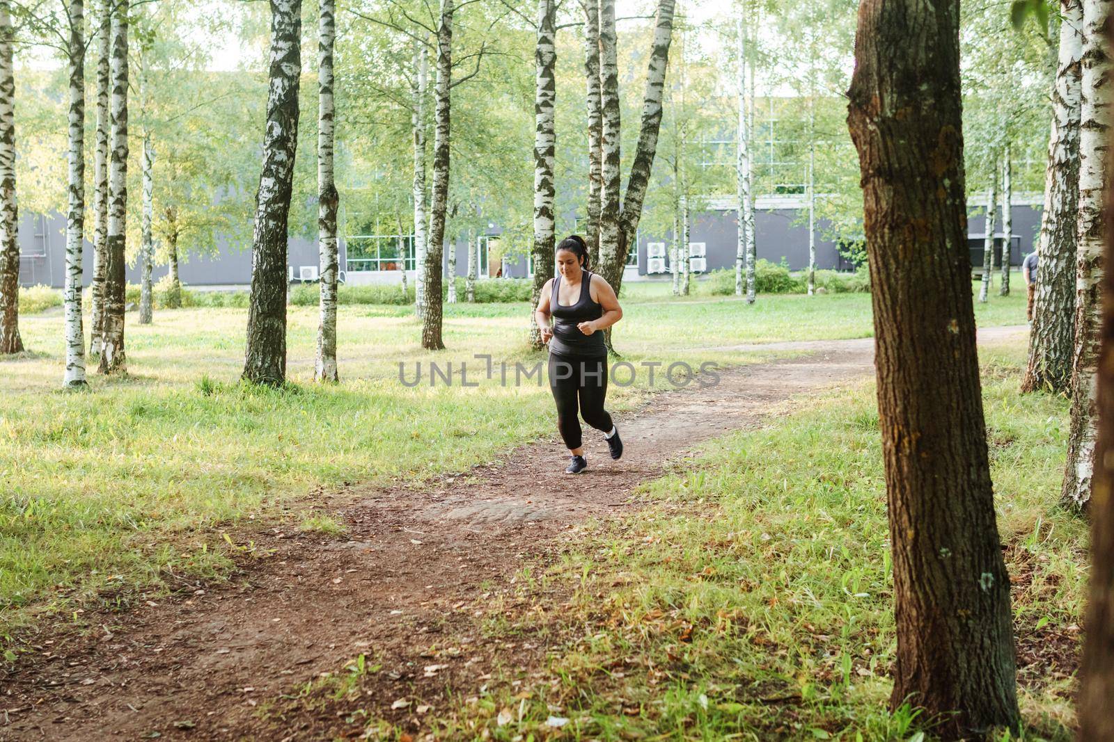 A charming brunette woman plus-size body positive practices sports in nature. by Annu1tochka