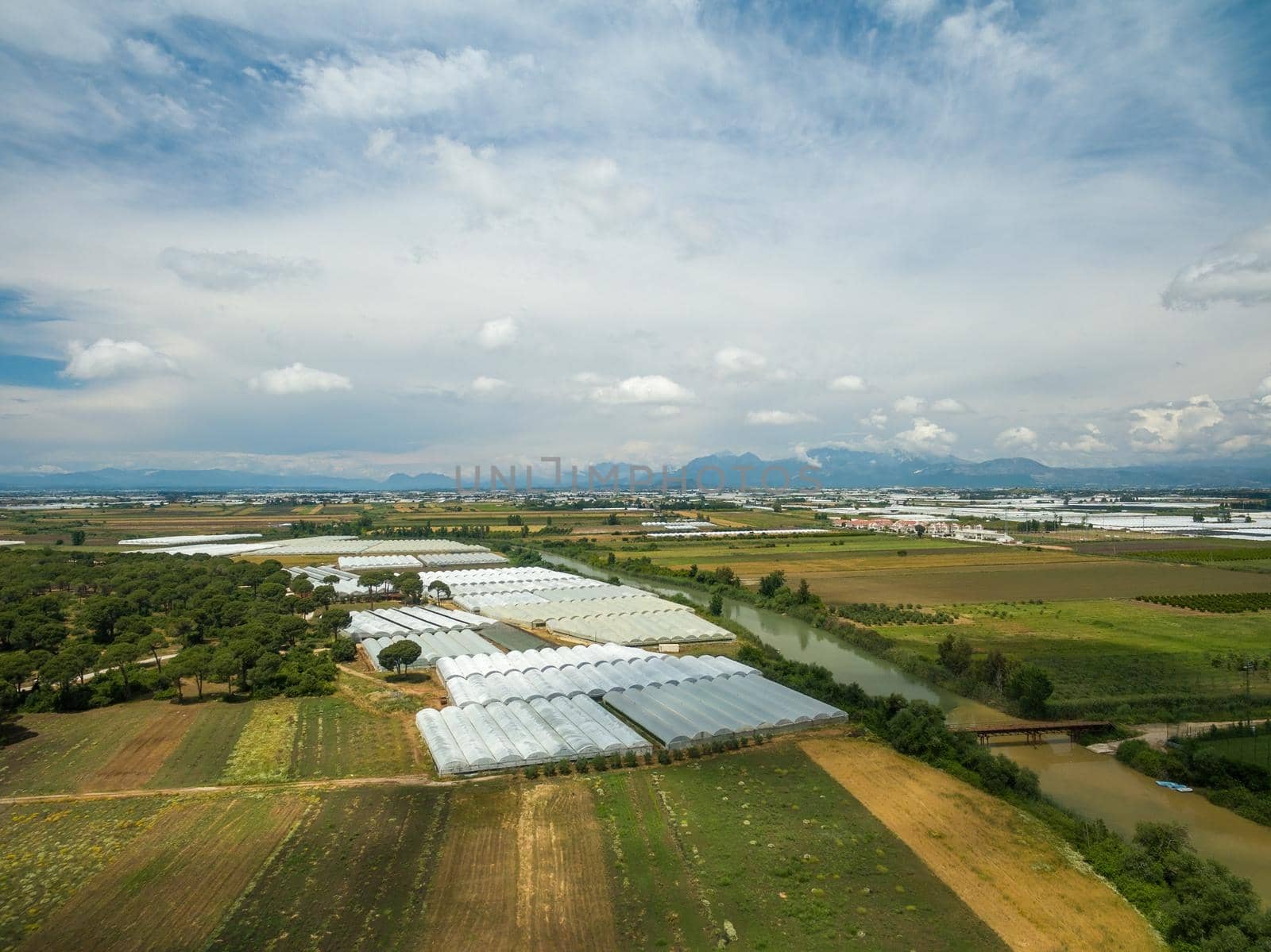 Aerial take of photo vegetable greenhouse by the roadside near the town