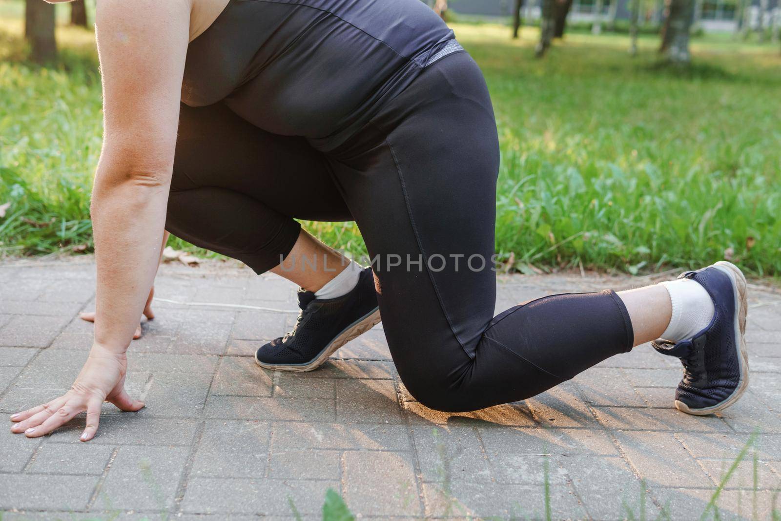 A charming brunette woman plus-size body positive practices sports in nature.