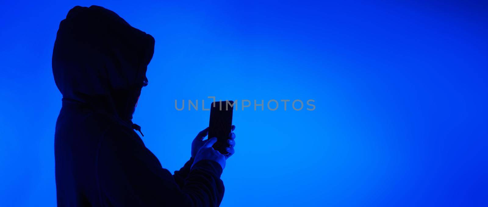 Digital security Concept. Anonymous hacker with mask holding smartphone hacked. by gnepphoto