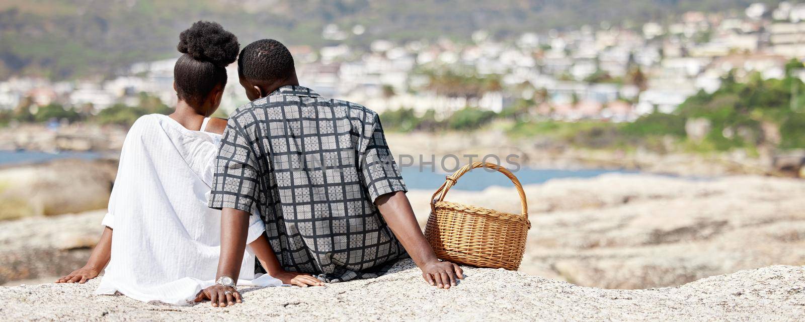 Couple, love and beach picnic for black woman or man on summer South Africa holiday near sea, water or ocean city. Safety, trust or security with zen people and view on nature rock on travel vacation.