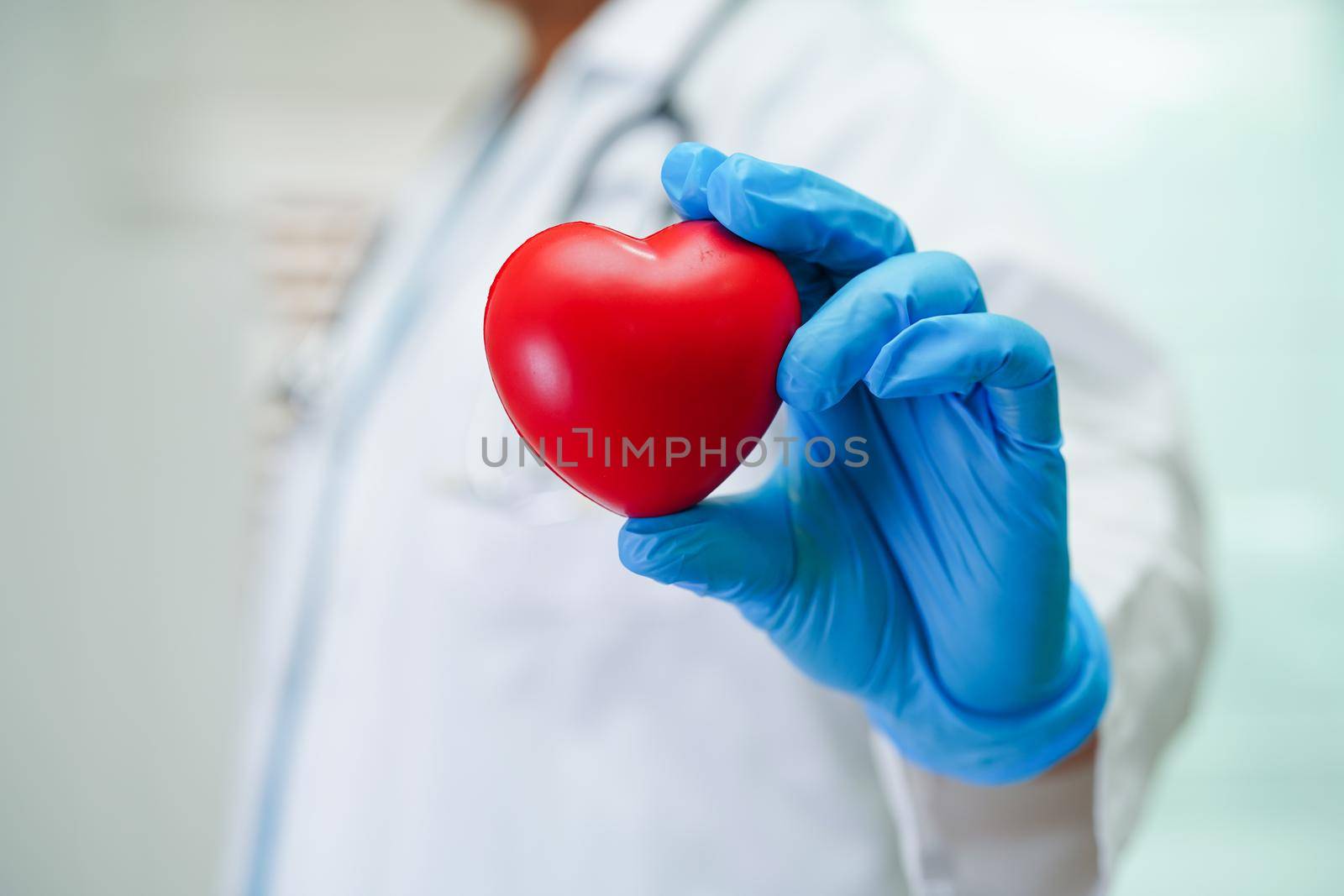 Asian woman doctor holding red heart for health in hospital.