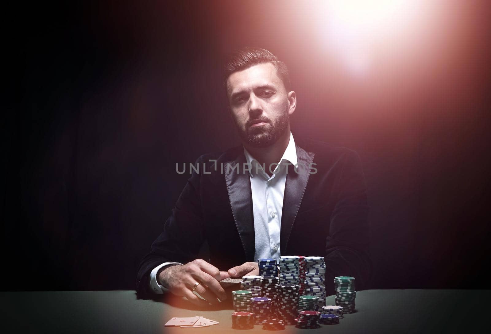 Young man sitting at the poker table with his chips and cards in front of him