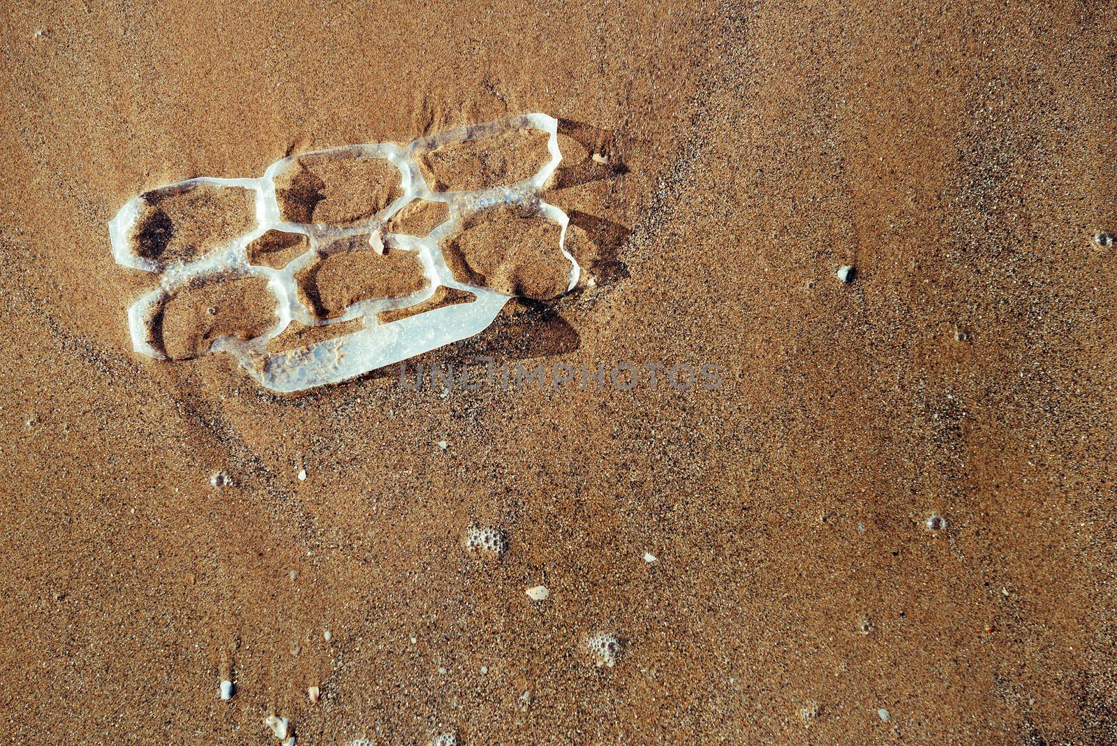 background of a plastic rings lying on the sand of the beach polluting the sea and the marine life, concept of pollution control of the oceans by plastic, copy space for text