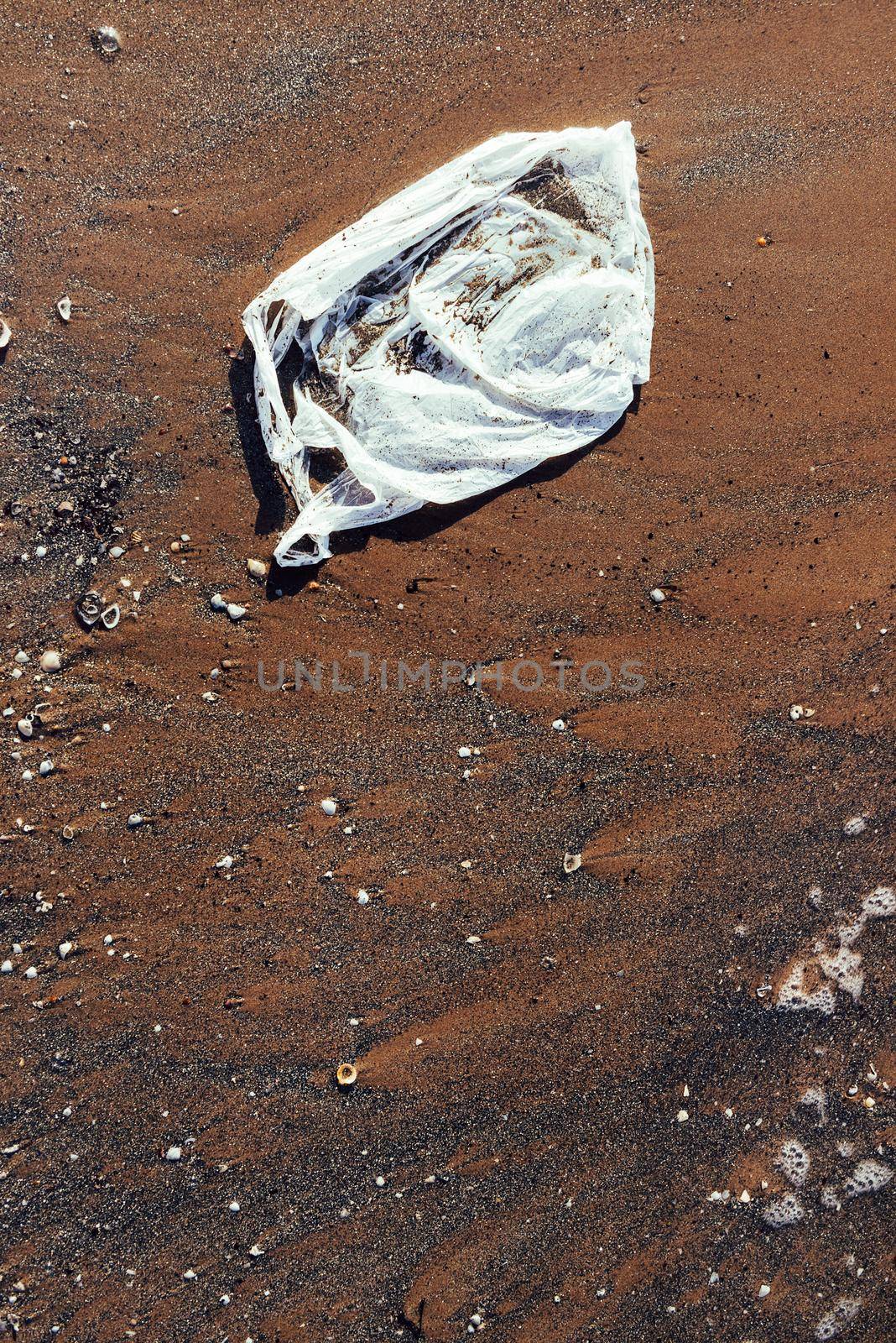 plastic bag contaminating the beach, seashore and water pollution with plastics concept, trash at the seaside, top view of an environmental problem