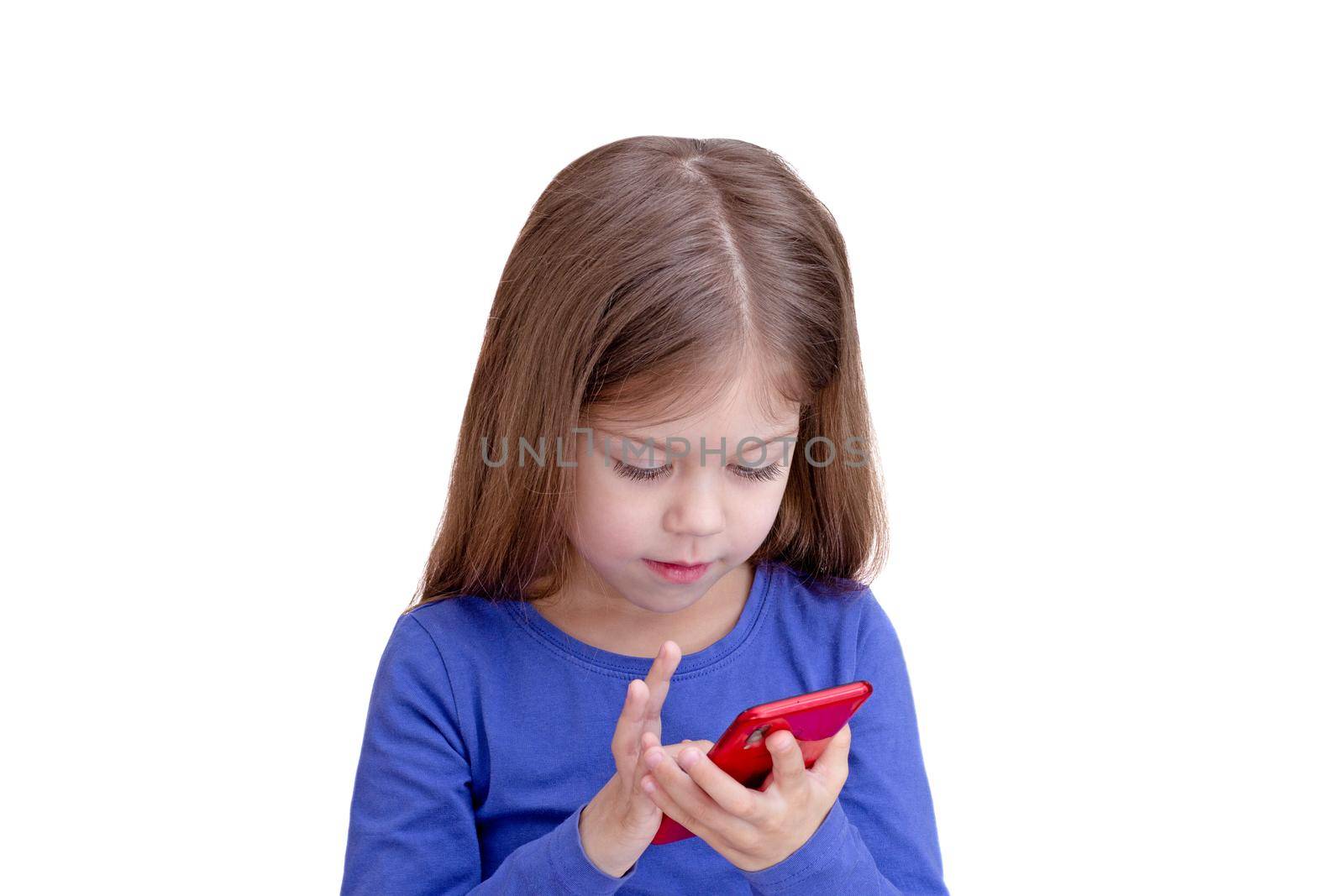 Serious child looking at mobile phone and touching screen , isolated on white background waist up caucasian little girl of 5 years in blue