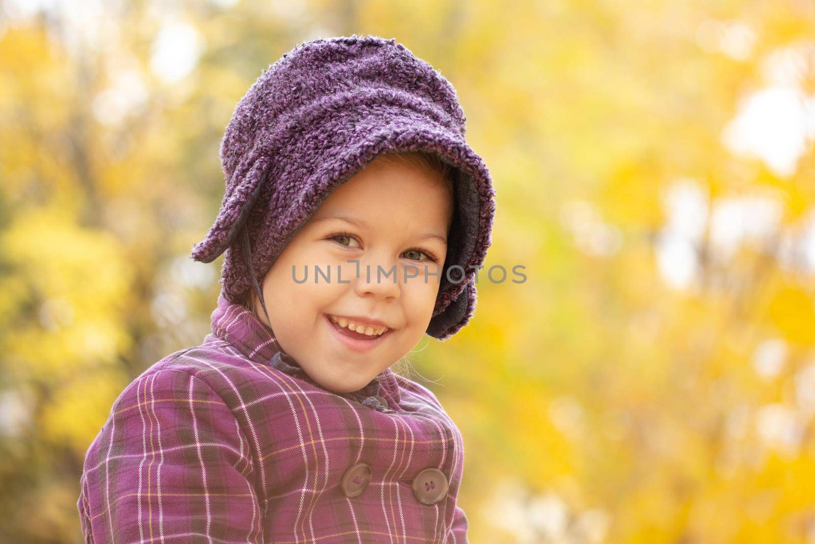 Portrait of caucasian five years old little girl looking at camera in autumn park with yellow light